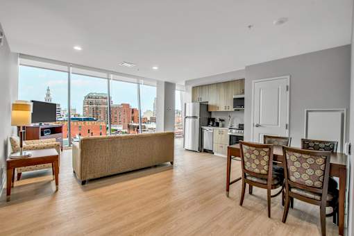 A living room with a couch, chairs, and a view of the city.