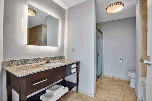 A bathroom with a sink, mirror, toilet and shower.