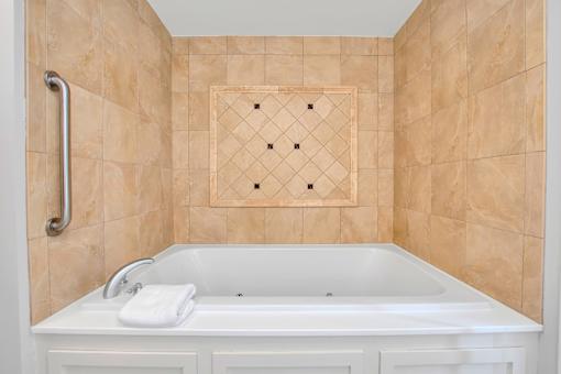 A white bathtub with a towel on the side and a tile wall.