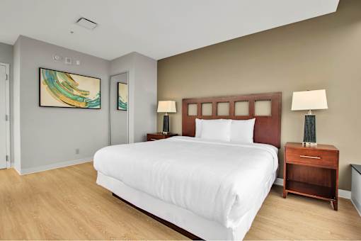 A bedroom with a large bed, two nightstands, and a painting on the wall.