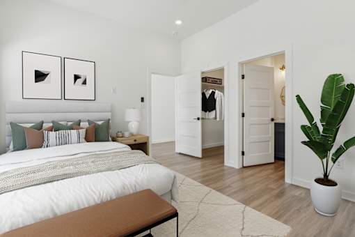 A bedroom with a large bed and a bench in the foreground.