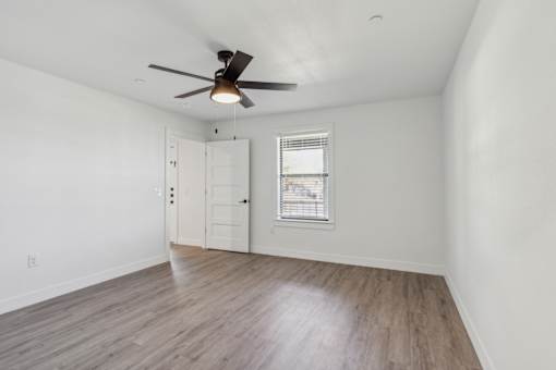 A room with a ceiling fan and a window with blinds.