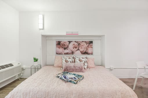 a bedroom with a bed and a painting of roses on the wall