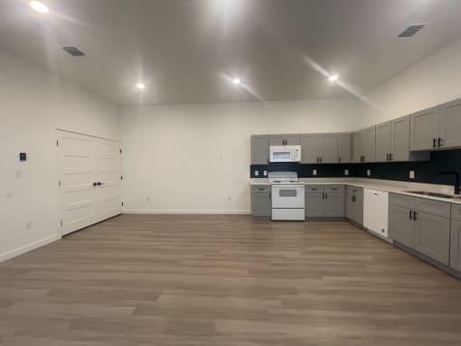 an empty kitchen with white cabinets and a wooden floor