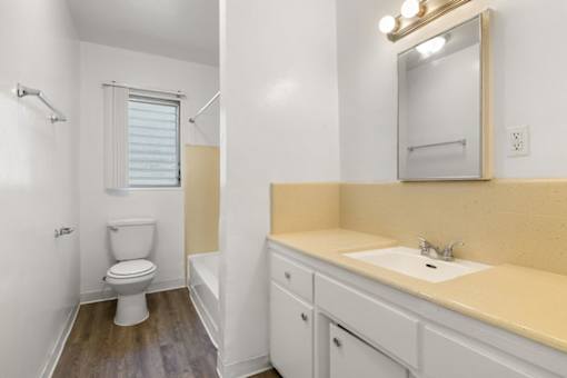 A white toilet sits in a bathroom next to a sink.