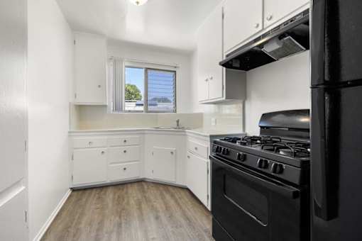 A black stove in a white kitchen with a window.