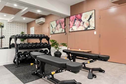 A gym room with a bench, weights, and a table.