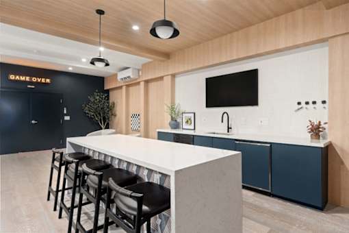 A modern bar area with a white counter and black stools.