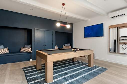 A pool table in a room with a blue couch and a television.