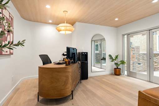 A modern office with a wooden desk and a black chair.