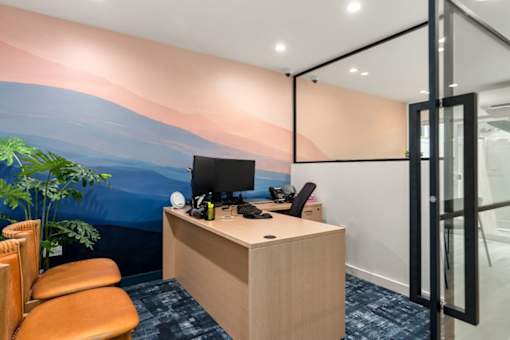 A room with a desk, chairs, and a computer.