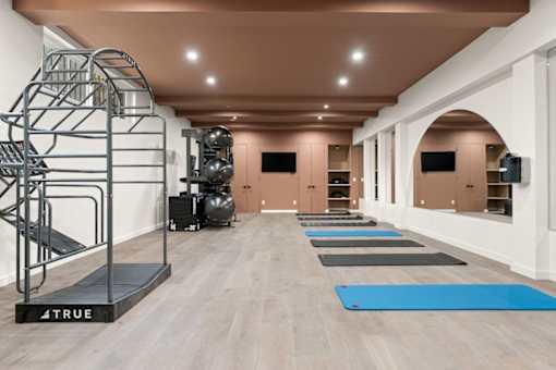A gym with a variety of equipment including a treadmill, weights, and a climbing wall.