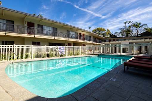 A swimming pool in front of a building with a fence around it.