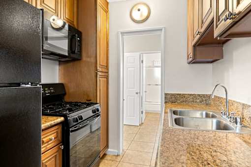A kitchen with a black fridge, microwave, and stove.