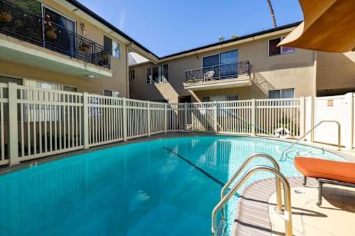 A swimming pool with a metal railing and a bench.