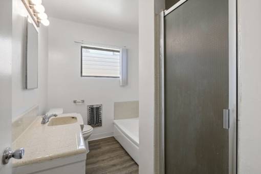 A bathroom with a sink, mirror, and bathtub.