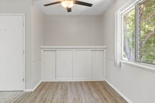 A room with a ceiling fan and a window with a view of trees.
