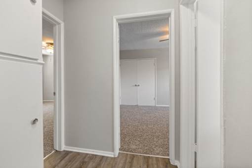 A white door is open to a room with a carpeted floor.