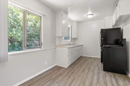 A kitchen with a black fridge and white cabinets.