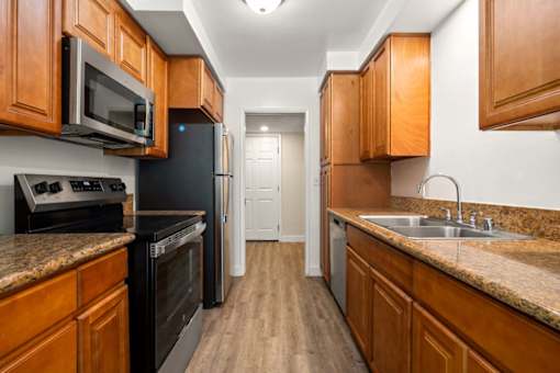 a kitchen with wooden cabinets and black appliances at White Oak Terrace Apartments, Encino, California