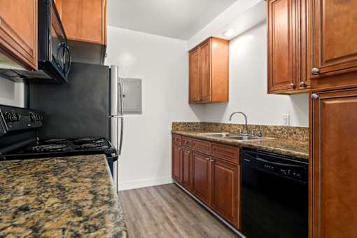a kitchen with granite counter tops and black appliances at White Oak Terrace Apartments, California