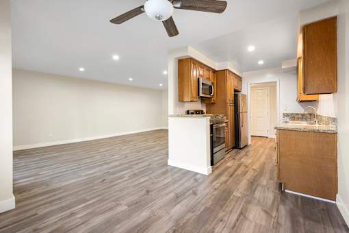 a kitchen and living room with hardwood floors and a ceiling fan