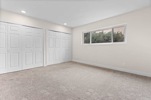 an empty room with three closets and a window
