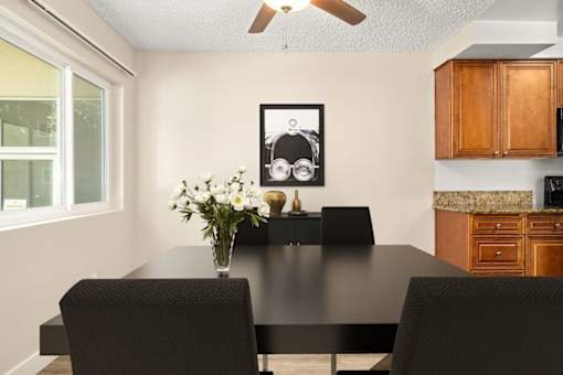 a dining room with a table and chairs and a vase of flowers at White Oak Terrace Apartments, California, 91316
