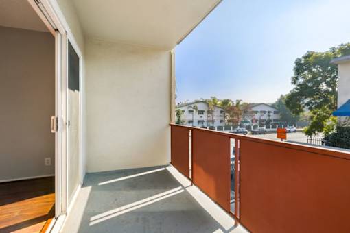 A balcony with a white door and orange railing.