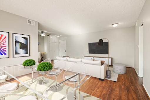 A modern living room with a glass coffee table and white furniture.