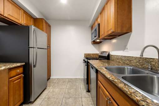 A kitchen with a black refrigerator and wooden cabinets.