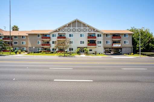 A large building with a white and brown facade sits next to a road.