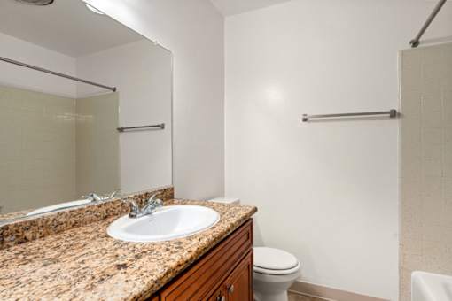A bathroom with a granite countertop and a white toilet.