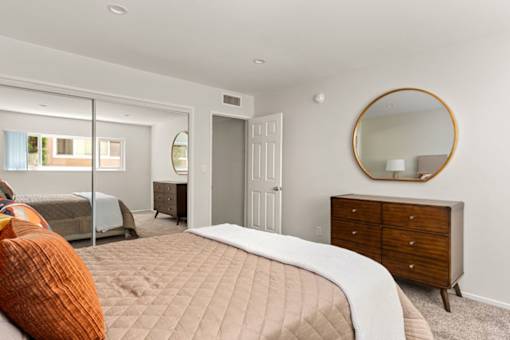 A bedroom with a bed, dresser, and mirror.