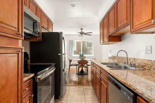 A kitchen with brown cabinets and a black refrigerator.