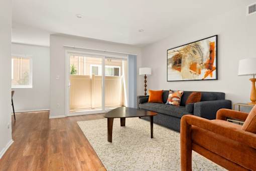 A living room with a couch, a chair, and a painting on the wall.