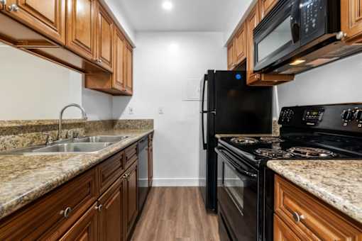 a kitchen with wood cabinets and black appliances at Lombardi Apartments, Woodland Hills, CA, 91367