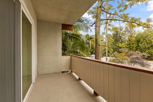 A balcony with a view of trees and a clear sky.