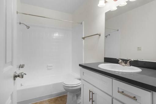 A white bathroom with a toilet, sink, and bathtub.