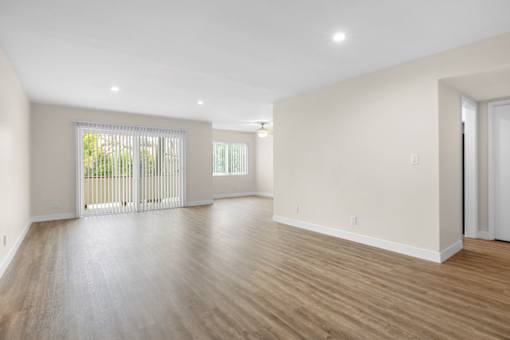 A spacious room with wooden flooring and white walls.