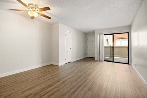 A room with a ceiling fan and wooden flooring.