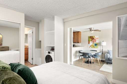 A bedroom with a large bed and a washing machine in the laundry area.