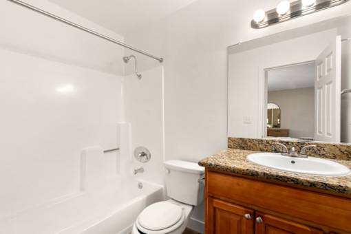 A white toilet sits next to a white bathtub in a bathroom.