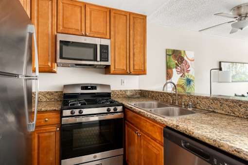 A kitchen with a stainless steel refrigerator, a stove, and a microwave above the stove.