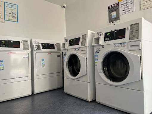 A row of white front load washing machines in a laundromat.