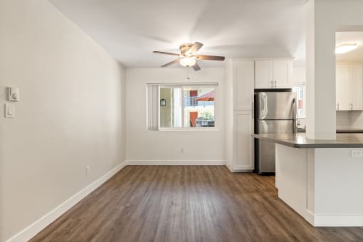 an empty living room with a kitchen and a ceiling fan at Parkway Terrace Apartments, Culver City, California