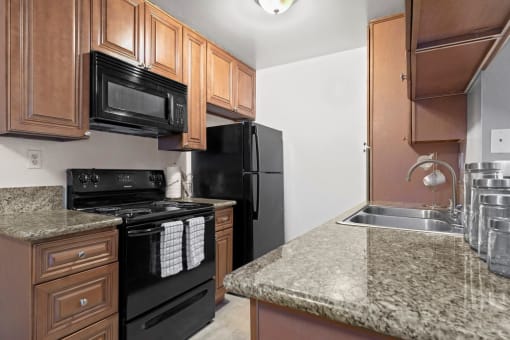 Studio apartments in Mar Vista CA - Vista - Kitchen with Sandy Granite Countertops, Wooden Cabinetry, Microwave, Oven, Stove, and Refrigerator, and Dual Sink