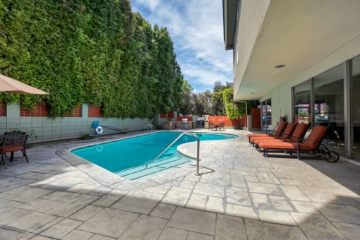Encino CA Apartments for Rent - White Oak Terrace - Blue Outdoor Pool with Poolside Seating with Greenery on Enclosure