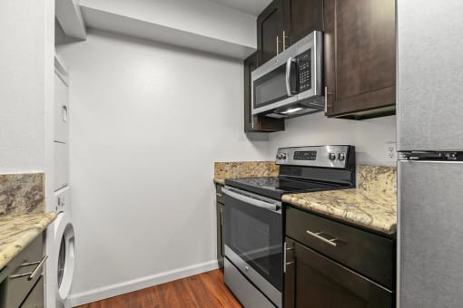 Kitchen with White Walls, Stainless Steel Appliances, Marble Countertops, and Espresso Cabinetry at The Meadows at Westlake Village Apartments, CA, 91361