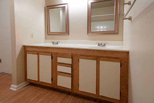 A bathroom vanity with a white countertop and wooden cabinets.